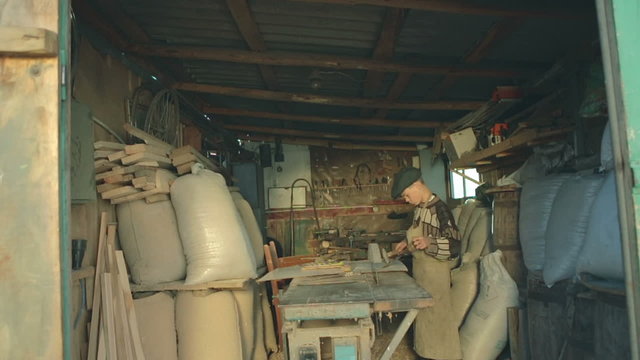 At his workshop teenager operates a chisel. The scene is illuminated by a beautiful evening light