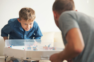 Father with son enthusiastically playing with table hockey
