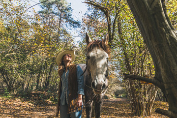 Pretty girl standing by her grey horse