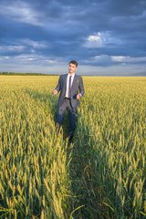 happy farmer, businessman, standing in wheat field with his hands and thumbs up