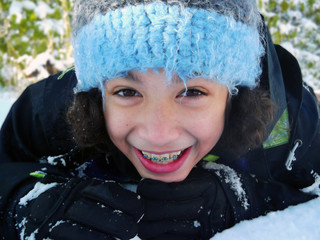 Snow smile close up/ close up of child in braces laying in snow