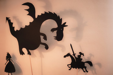 Fototapeta premium Shadow Puppets of Dragon, Princess and Knight z jasnym świecącym ekranem teatru cieni w tle.