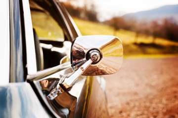 Closeup view on a chrome mirror of a classic car