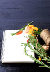 cover cookbook notebook on a black wooden background spices recipe for garlic thyme pepper