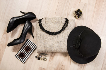 Winter sweater and accessories arranged on the floor.Woman black with silver accessories, high...