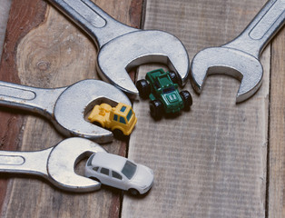 little toy cars near the wrenches on a wooden surface.metaphor car service.toned
