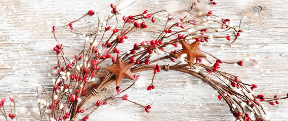 Christmas wreath with red and white berries and rusty metal stars, long narrow format for web design, toned image