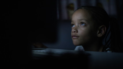 4K Young child watches a computer screen at night in the dark - Powered by Adobe