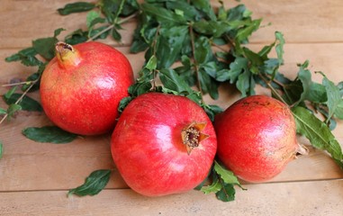 Pomegranate ripe juicy fruits on the wooden table with leaves