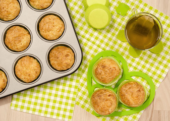 Muffins in a tray and on green napkin. Cup a tea and muffins on on heart shape holder.