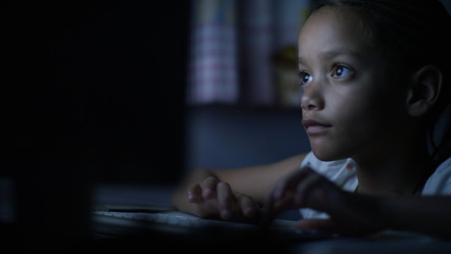 4K Young child typing on a keyboard in the dark at night