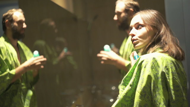 Young couple in bathroom, woman applying hairspray and man antiperspirant 
