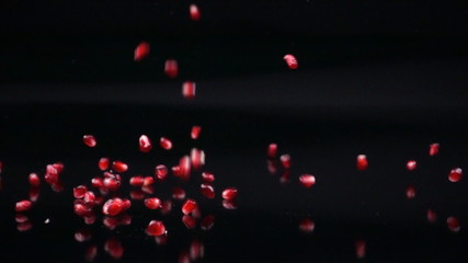 Fresh pomegranate seeds falling on black background in slow motion