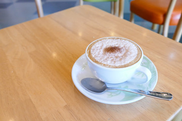 hot cappuccino coffee in a cup with saucer and spoon