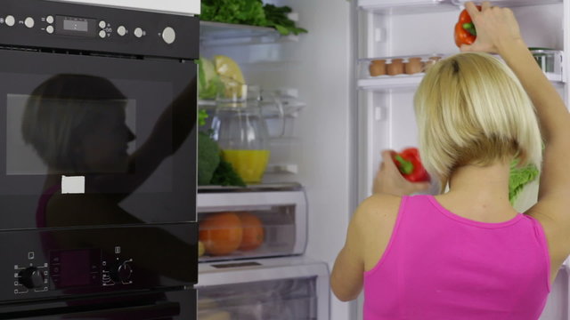 woman take vegetables from refrigerator red pepper excited
