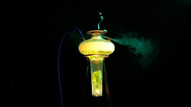 Colored yellow hookah with the smoke on black, close up 