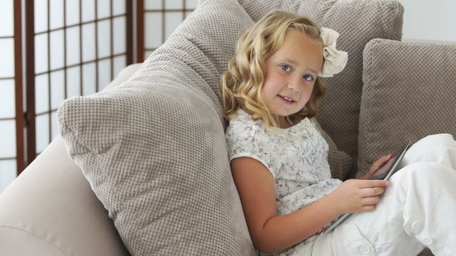 Girl resting on the couch and playing on the tablet pc
