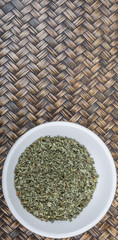 Dried basil leaves herbs over in white bowl over wooden background