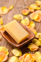 roses petals with soap in wooden bowl  on old wooden board