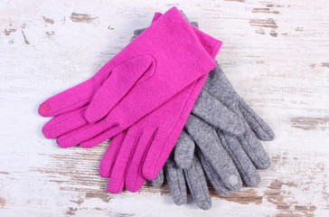 Pair of woolen gloves for woman on old wooden background