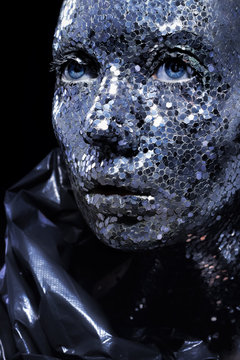 Beautiful face of a woman covered in big glitter Close up woman, silver pieses on body
