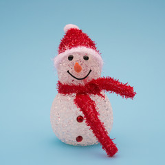 smiling toy christmas snowman with red scarf on blue