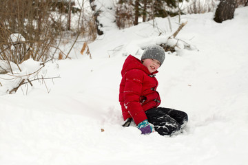 Fototapeta na wymiar Happy boy playing in a snowdrift outside in winter