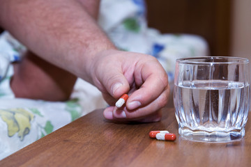Fototapeta na wymiar Hand with medicines on bedside table