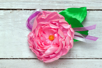 brooch handmade silk ribbons in the form of a pink flower on a wooden surface