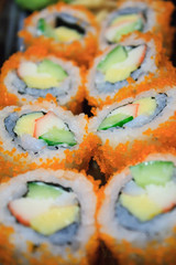 Sushi roll, row of California maki roll sushi with caviar on bla