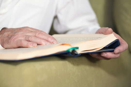 An old man hands reading Koran. Selective focus
