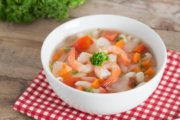 Macaroni with shrimp soup on white bowl.