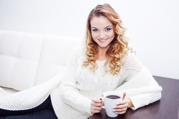 Young woman at home drinking hot coffee, wrapped in a scarf,  white background, place for your text