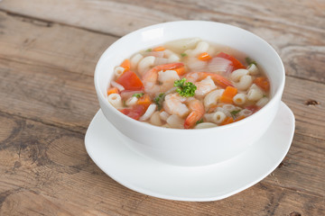 Macaroni with shrimp soup on white bowl.