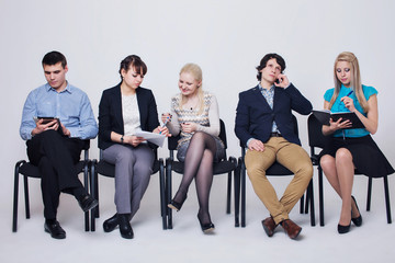 Люди в деловой официальной одежде сидят на стульях, разговаривают по телефону, читают, общаются на белом фоне
