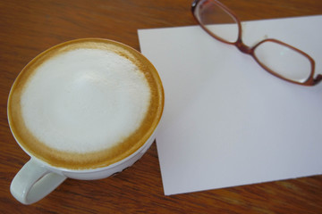 Cup of hot coffee and watercolor paper and glasses  put on the w