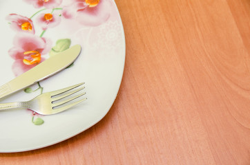 Empty plate with fork and knife on wood table