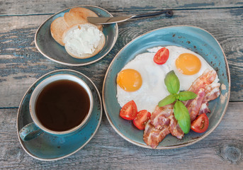 Fried eggs,  bacon, tomato, toast and a cup of coffee