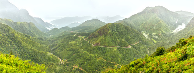 Panorama O Quy Ho Pass in the morning, Lao Cai, Vietnam with roads winding through the rugged mountain range. It was chosen as the Pass the four most beautiful and rugged Northwest Vietnam