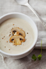 Cream soup with mushrooms champignon and potato in white bowl, vintage style, top view
