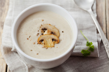 Cream soup with mushrooms champignon and potato in white bowl, vintage style