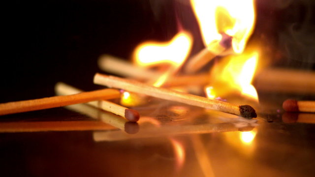Lit matches falling on black background