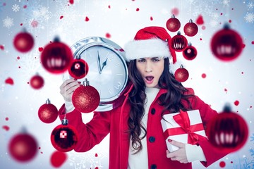 Composite image of surprised brunette holding a clock and gift