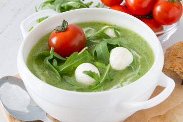 Arugula and tomatoes puree soup in white bowl