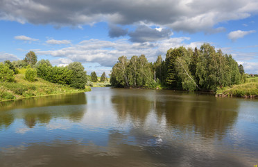 Field road among the flowers and along the forest with 

clouds
