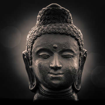 The bust of Buddha during the night with the city lights up in the bright bokeh