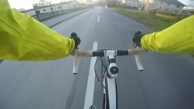 4K POV Road cycler cycling through the city into the sunset