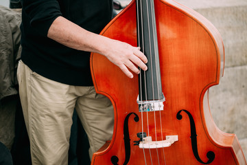 Fototapeta premium Street Busker performing jazz songs outdoors. Close up contrabas