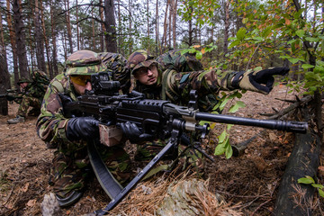 Soldier demonstrates target to gunner in forest/Team of armed soldiers in uniform preparing to open...