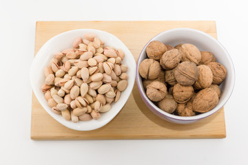platefuls of different nuts stand on a plate on a white backgrou
